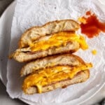 A Taylor ham, egg, and cheese sandwich with jammy eggs, drippy cheese, and hot sauce.