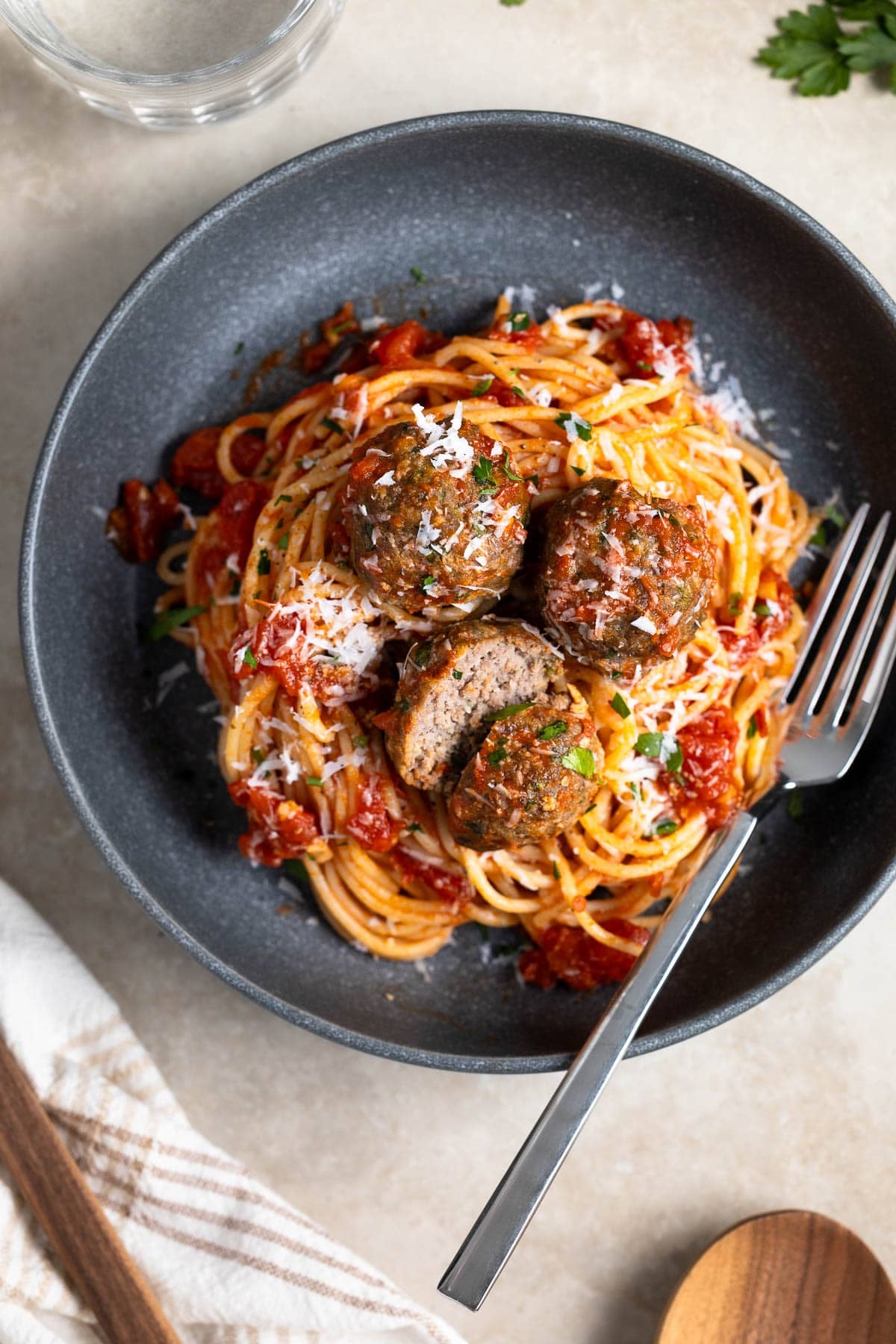 A plate of spaghetti and beef meatballs with a fork.