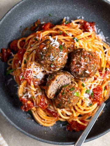 A plate of spaghetti and beef meatballs with a fork.