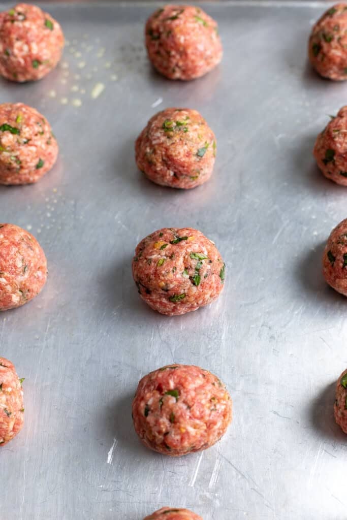 Rolled meatballs on a sheet pan before baking.