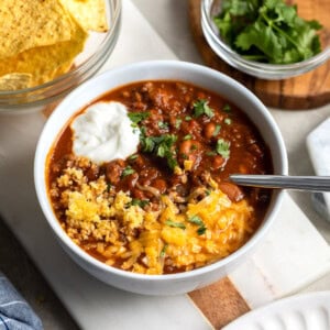 A bowl of turkey chili made in the Instant Pot topped with sour cream, cornbread, cheese, and cilantro.