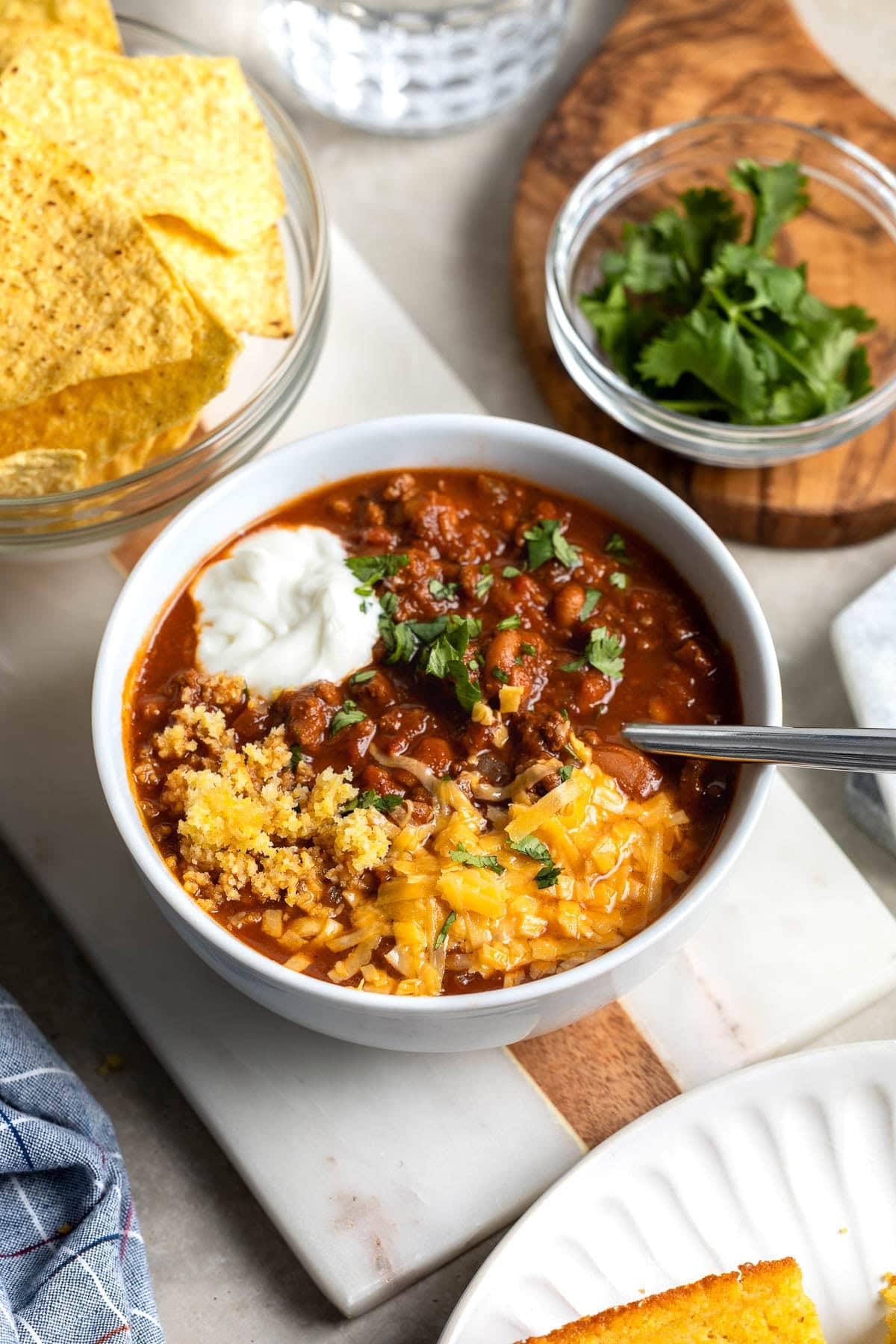 A bowl of turkey chili made in the Instant Pot topped with sour cream, cornbread, cheese, and cilantro.