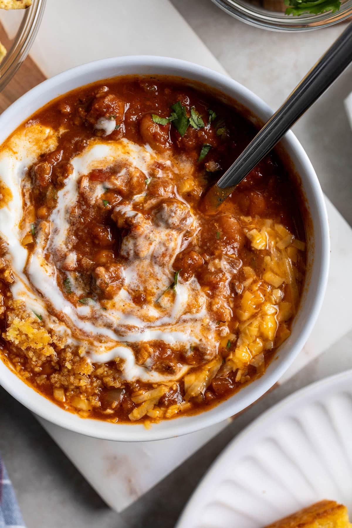 Sour cream and toppings stirred into a bowl of hot turkey chili.
