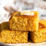 A stack of polenta cornbread topped with honey and melting butter.