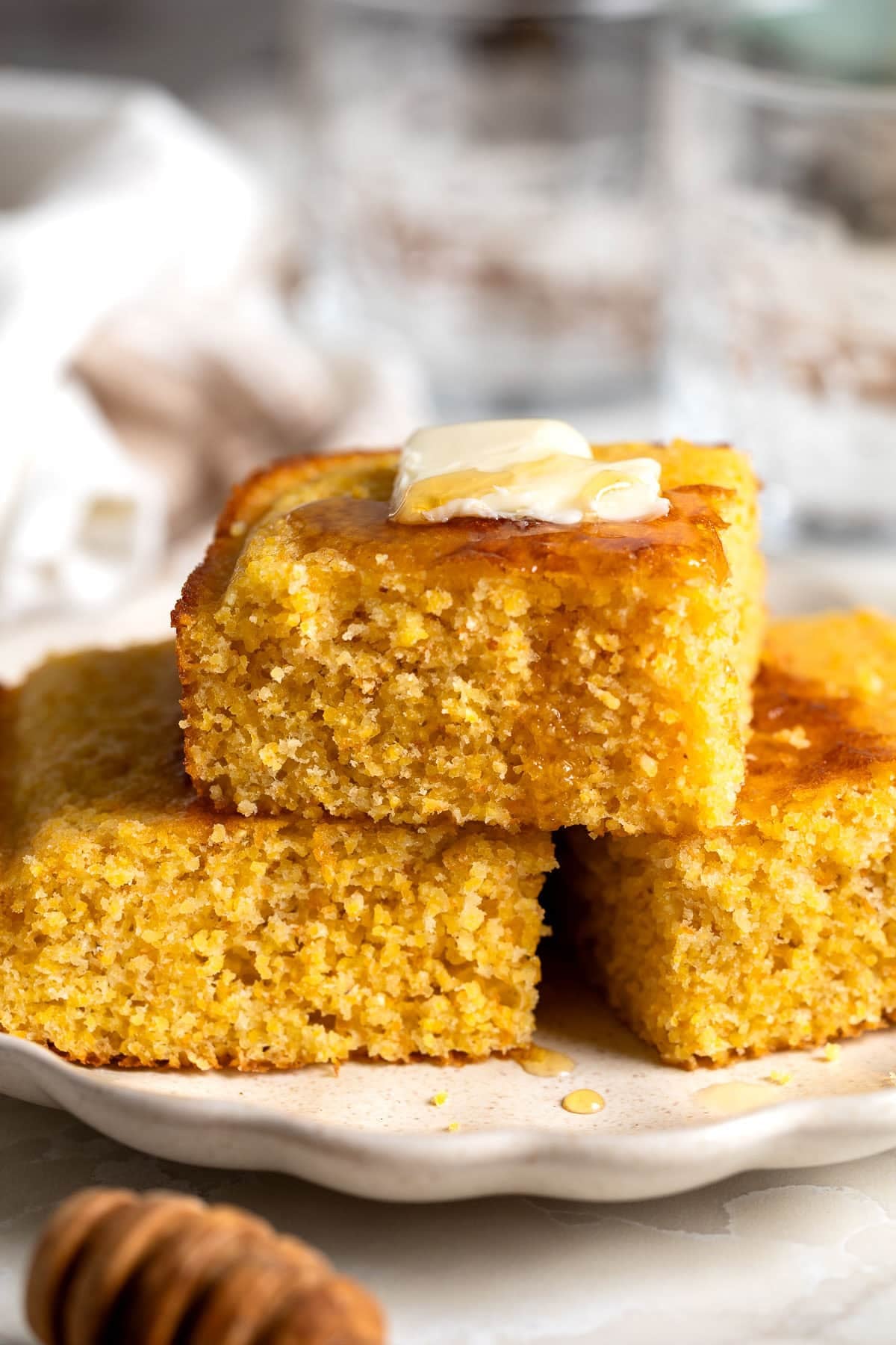 A stack of polenta cornbread topped with honey and melting butter.