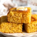 A stack of polenta cornbread topped with honey and melting butter.