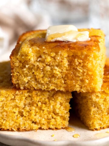 A stack of polenta cornbread topped with honey and melting butter.