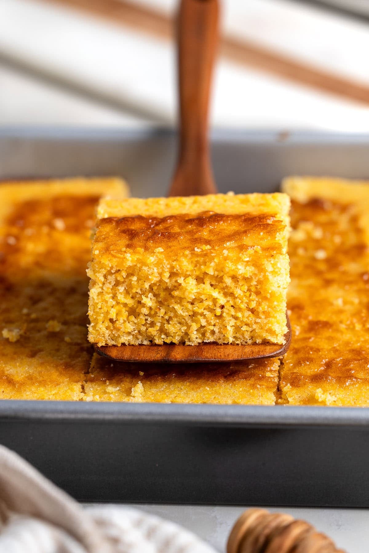 A spatula lifting a square of polenta cornbread out of the pan.