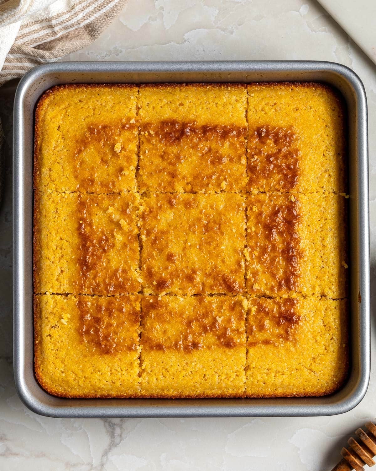 A pan of polenta cornbread sliced into nine equal squares.
