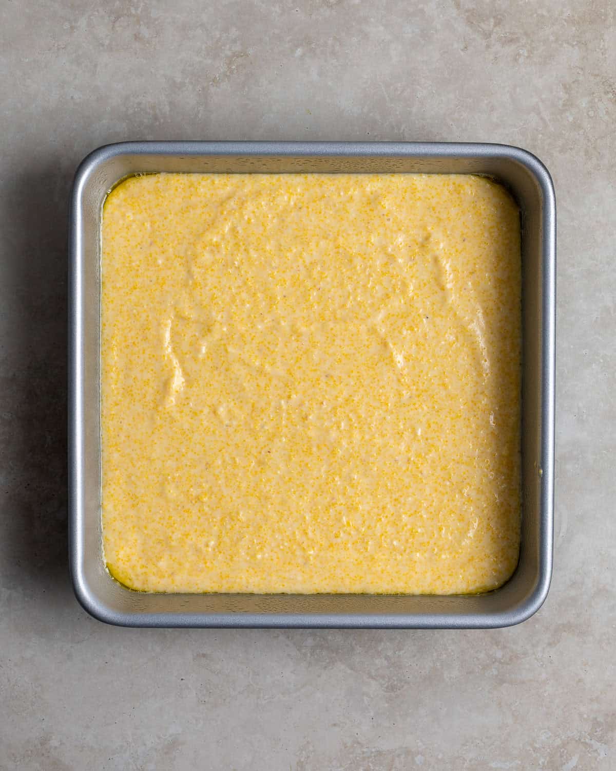 Polenta cornbread poured into a square baking dish.