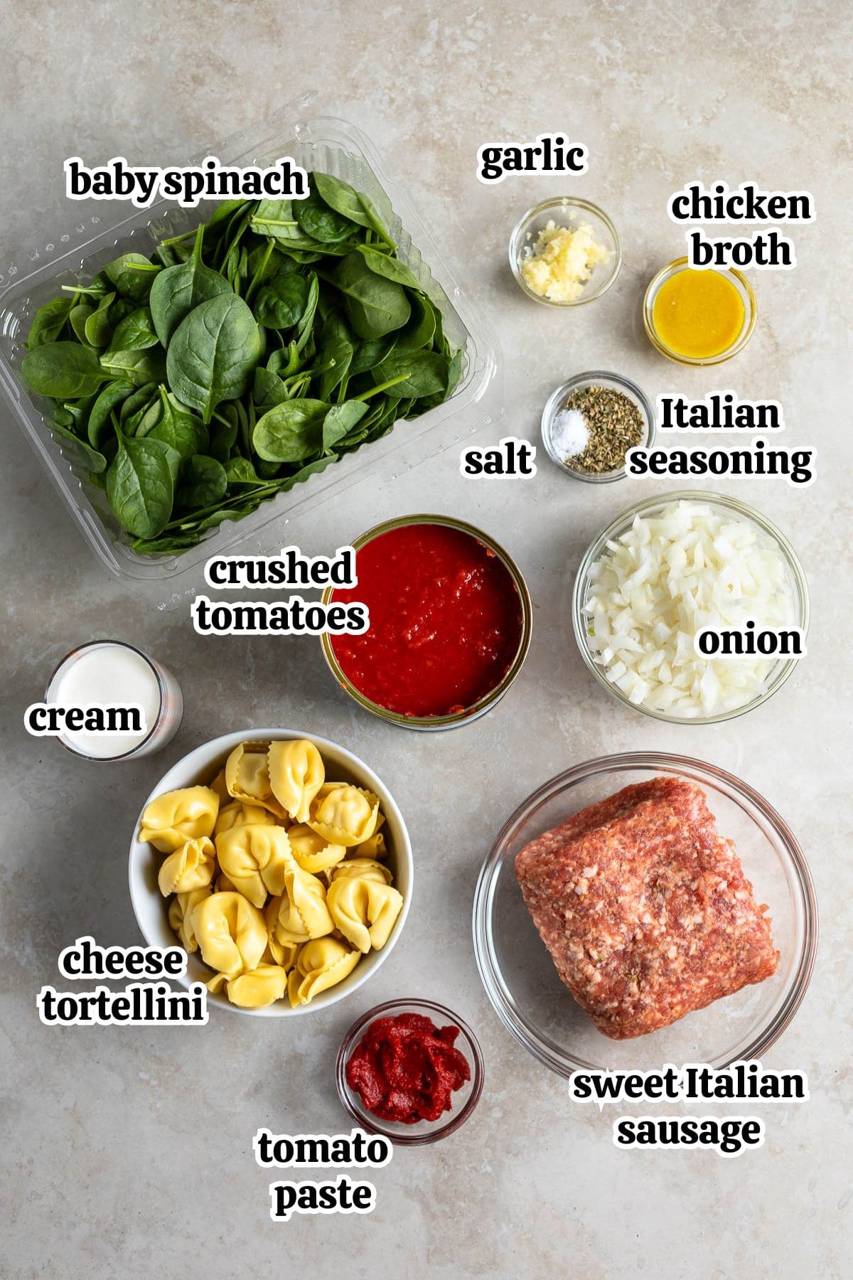Text-labeled ingredients needed to make sausage tortellini soup in separate bowls.