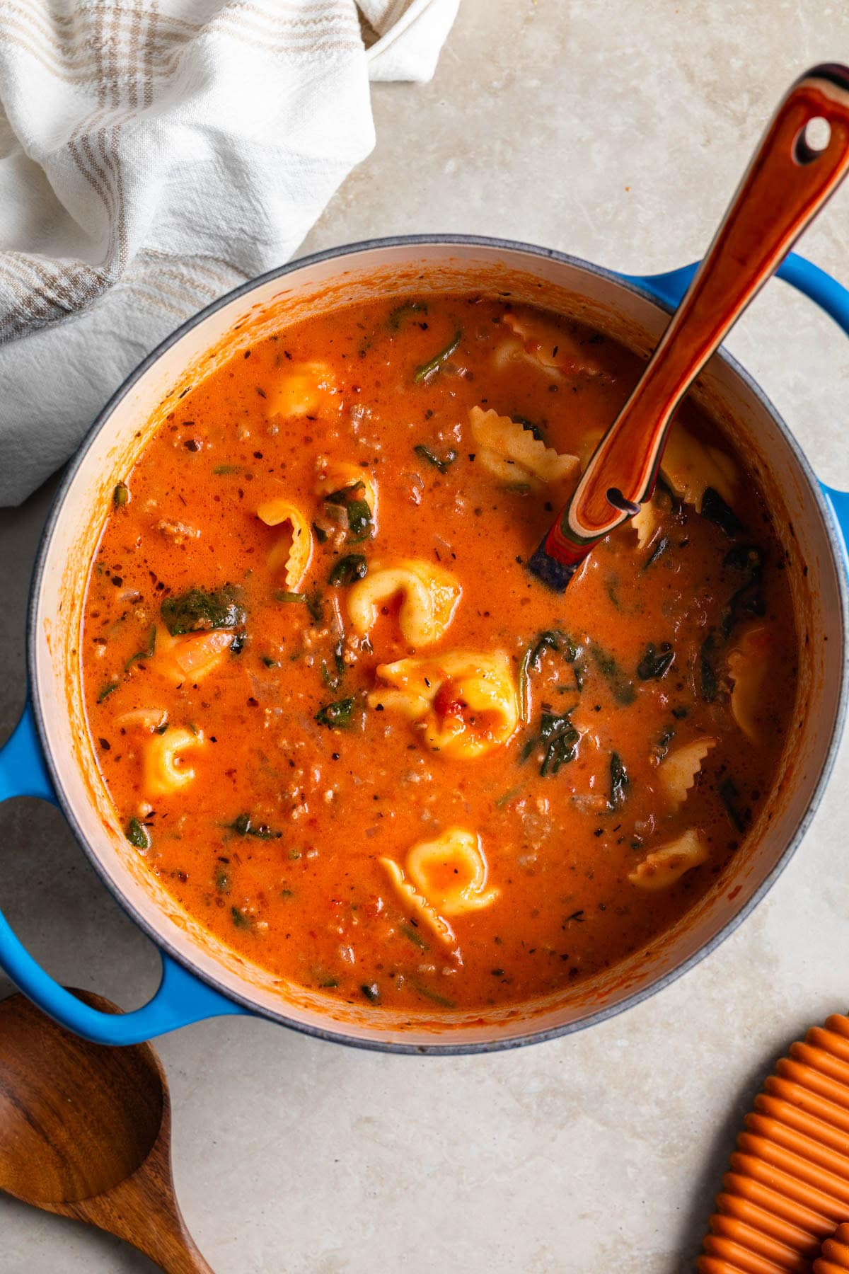 A pot of sausage tortellini soup after stirring in the spinach and cream.