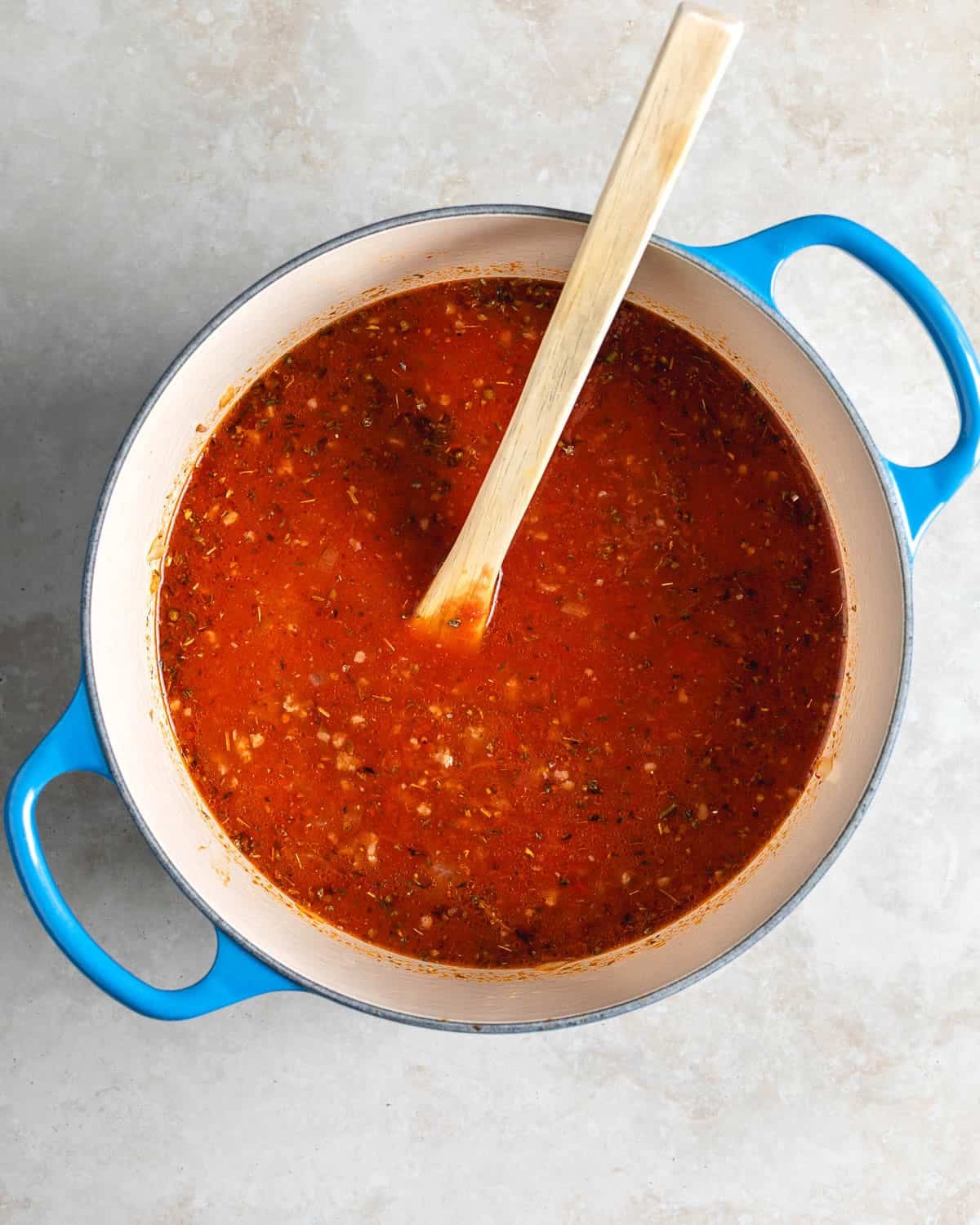 Chicken broth and crushed tomatoes added to the pot.