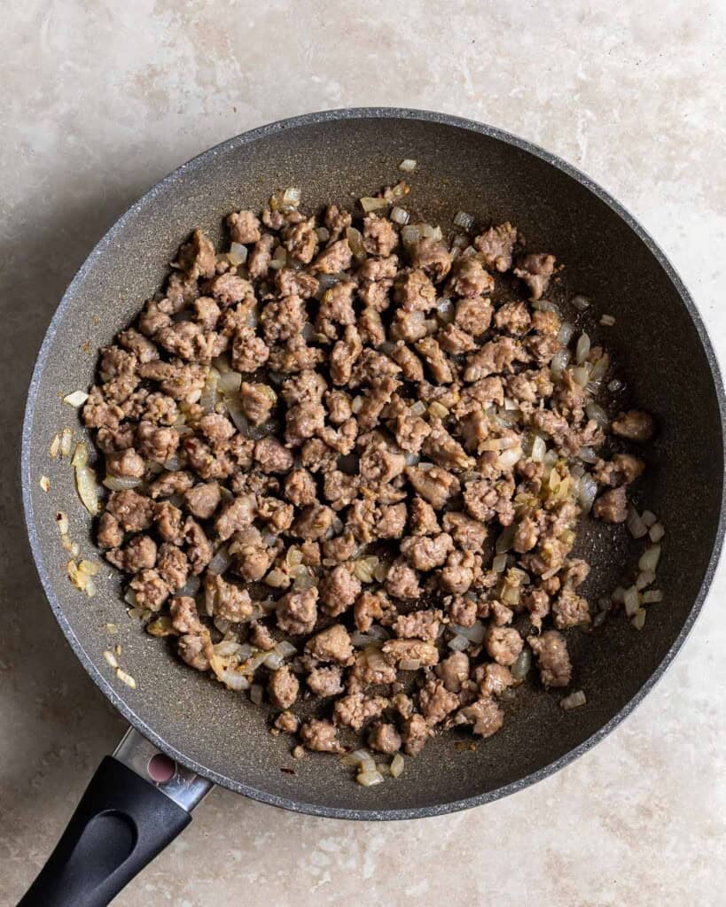 Crumbled Italian sausage, onion, and garlic saut&eacute;ed in a pan.