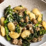 Toasted gnocchi with sautéed broccoli rabe and Italian sausage crumbles in a shallow bowl.