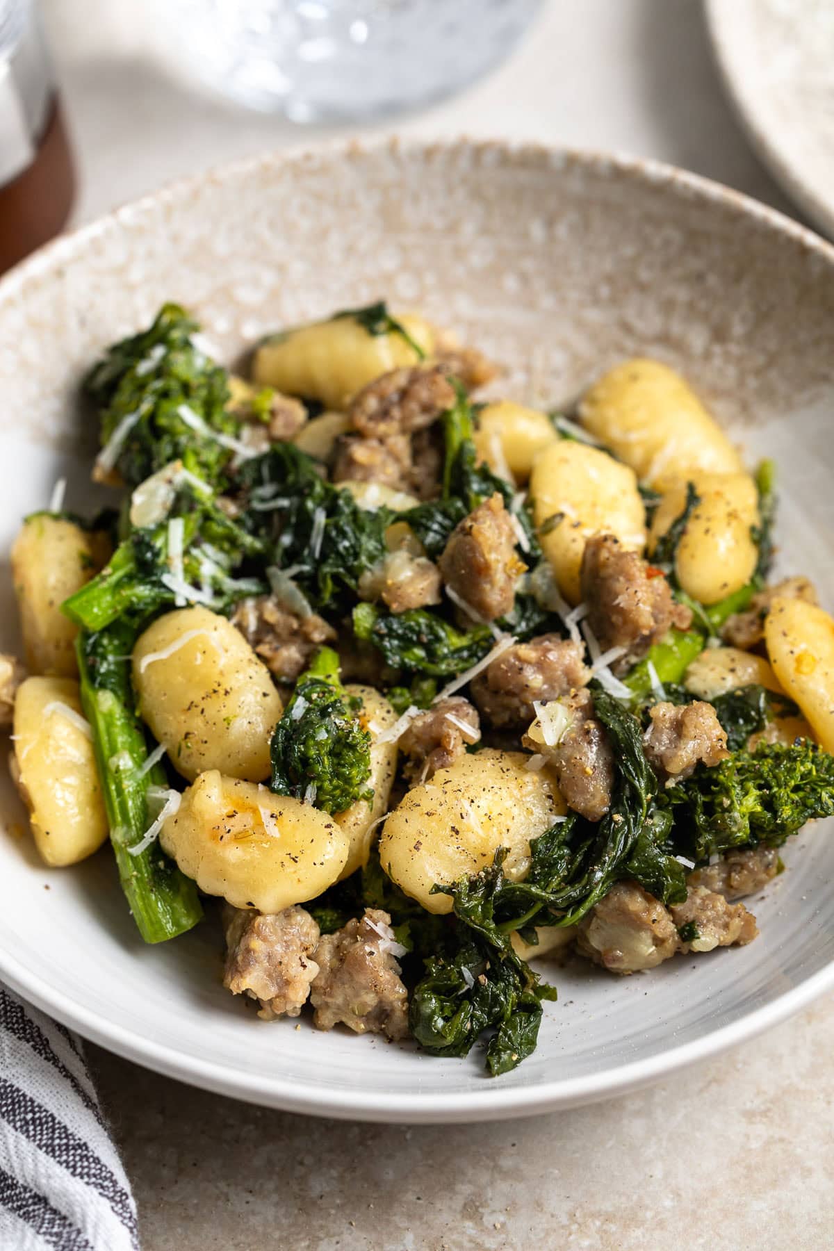 Toasted gnocchi with saut&eacute;ed broccoli rabe and Italian sausage crumbles in a shallow bowl.