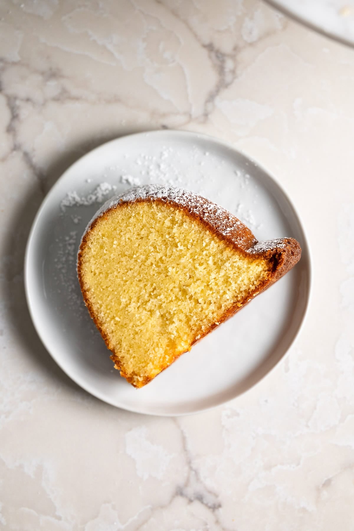 A slice of powdered sugar dusted Philly fluff cake on a plate.