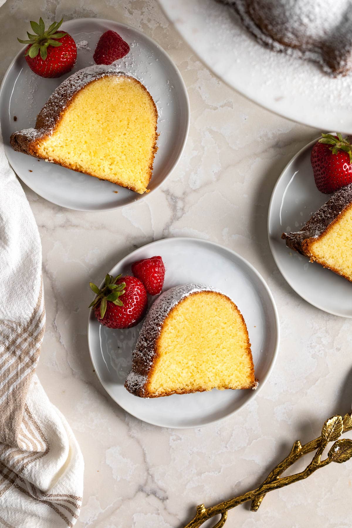 Three slices of Philly Fluff pound cake on plates with berries.