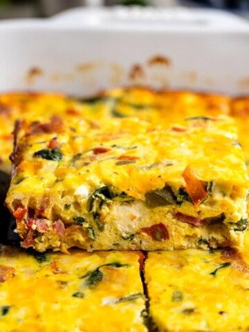 A side profile view of a wedge of ricotta egg bake being lifted out of the pan by a spatula.