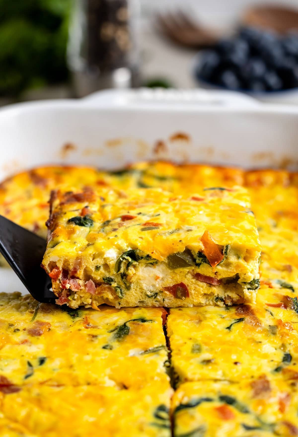 A side profile view of a wedge of ricotta egg bake being lifted out of the pan by a spatula.