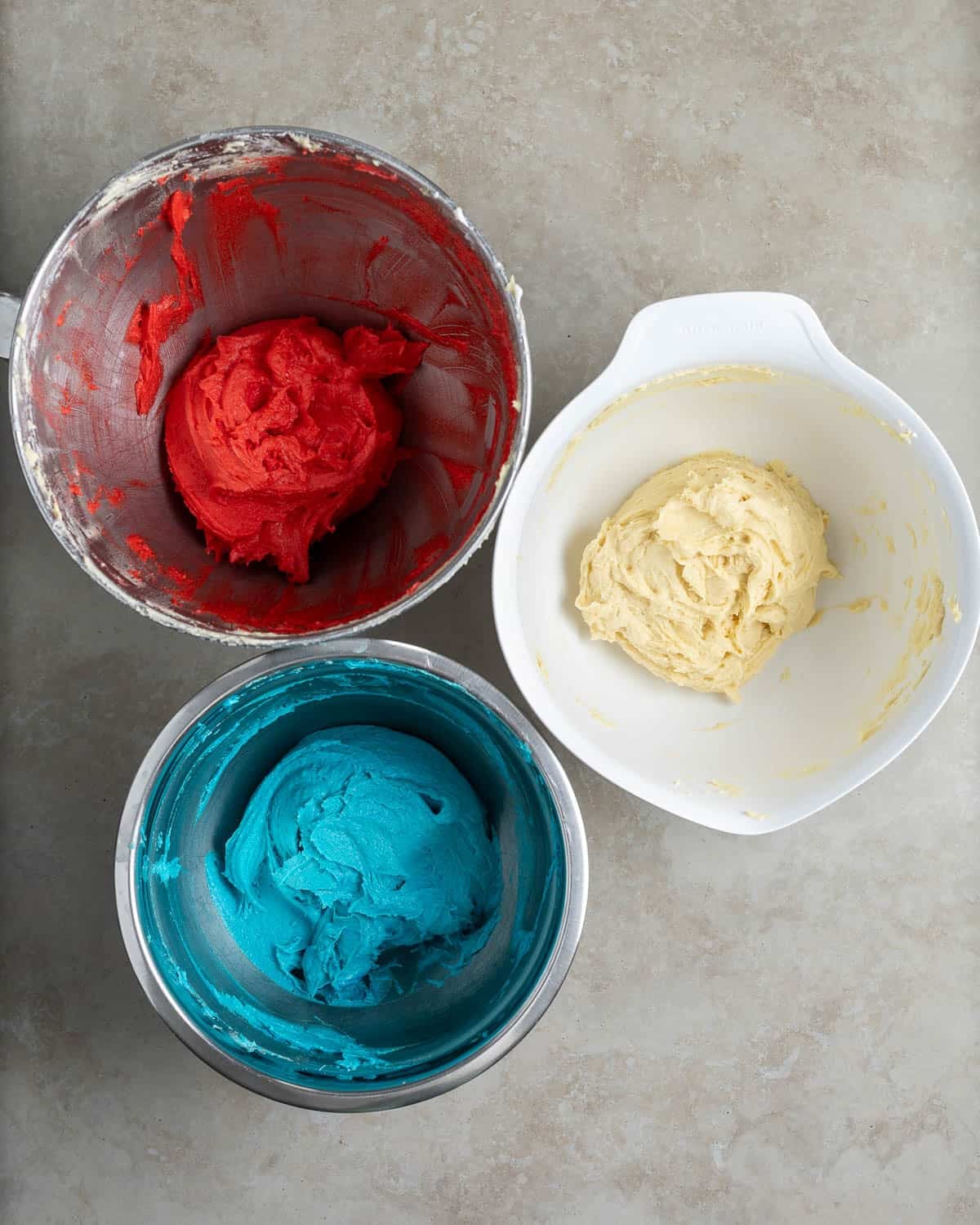 Red, white (uncolored), and blue batter in three separate bowls.