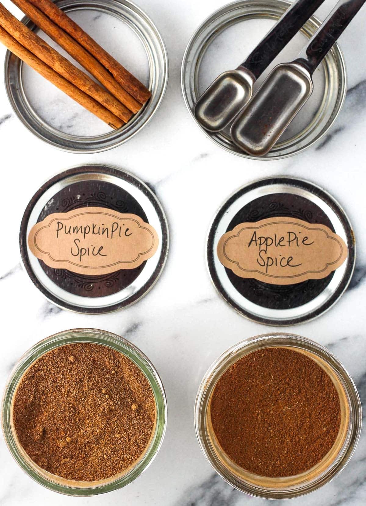 Pumpkin and apple pie spices in small glass jars with labeled lids.