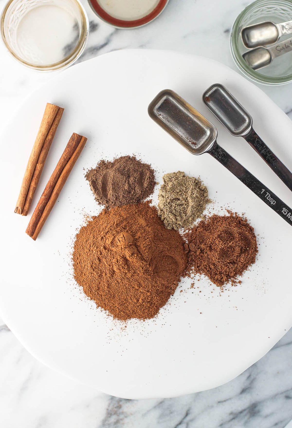 Apple pie spice ingredients in separate piles on a plate.