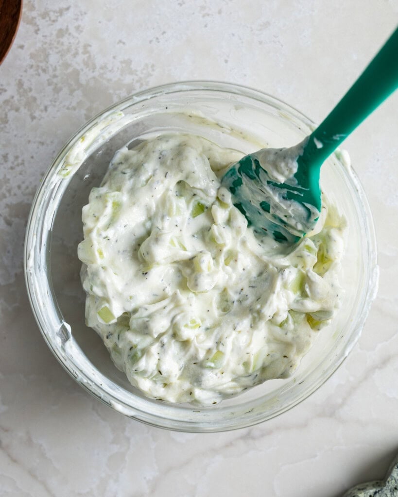 Combined cucumber yogurt sauce in a bowl with a spatula.