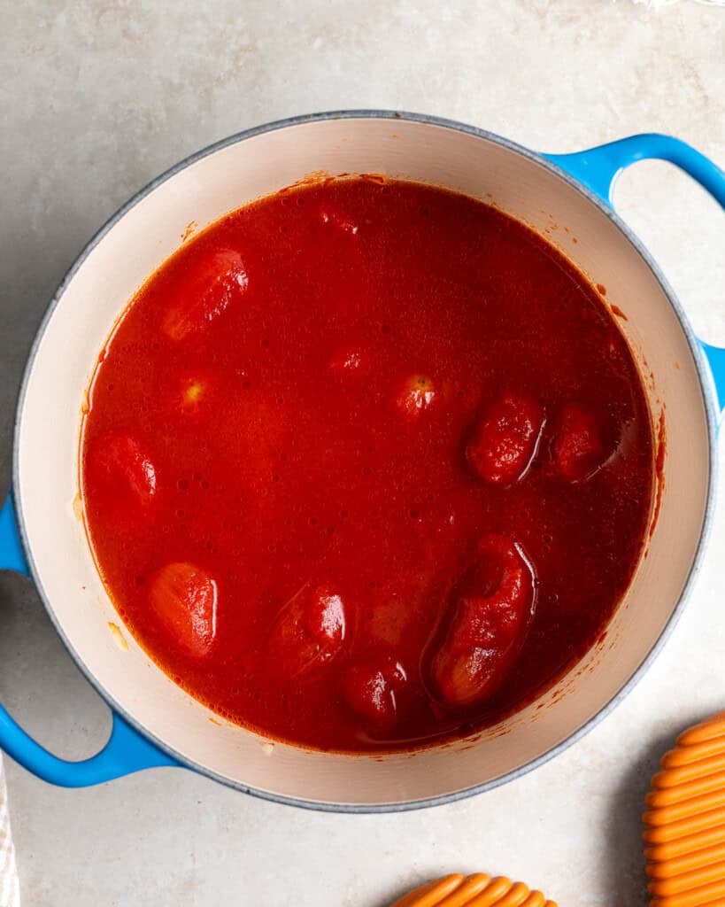 Most of the tomato soup ingredients poured into the pot before simmering.