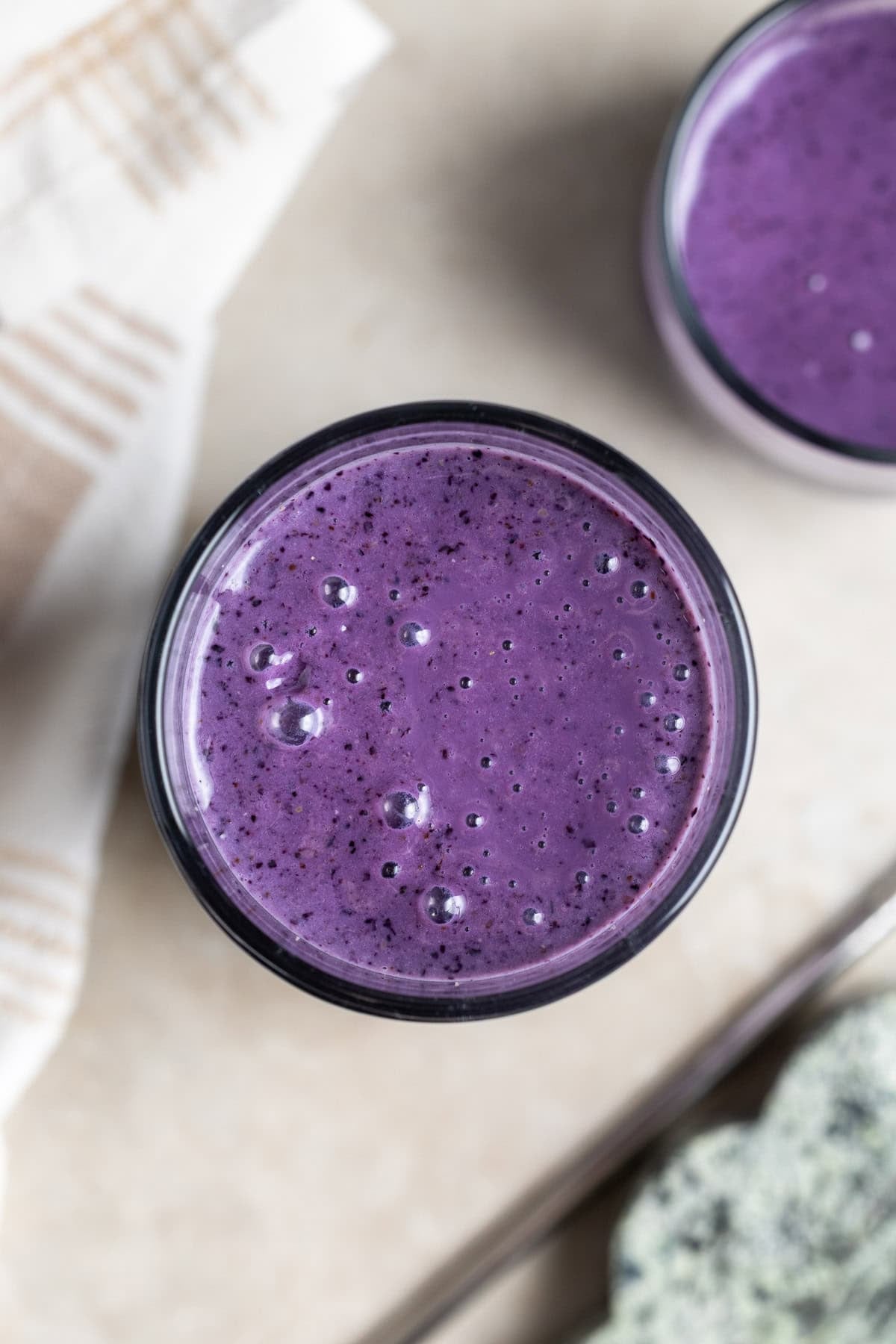 A top-down view of a wild blueberry smoothie in a tall glass.