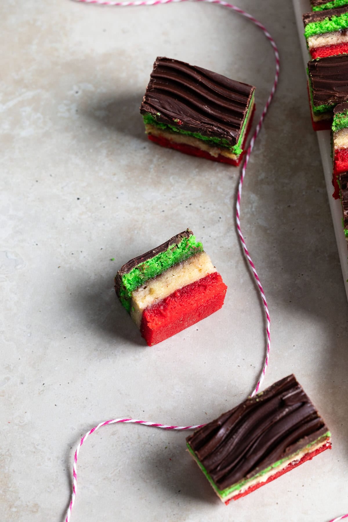 An assortment of Italian tricolor cookies around bakery twine.
