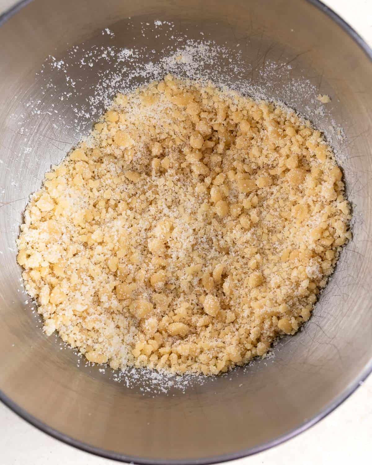 Almond paste in a stand mixer bowl crumbled into small bits combined with granulated sugar.