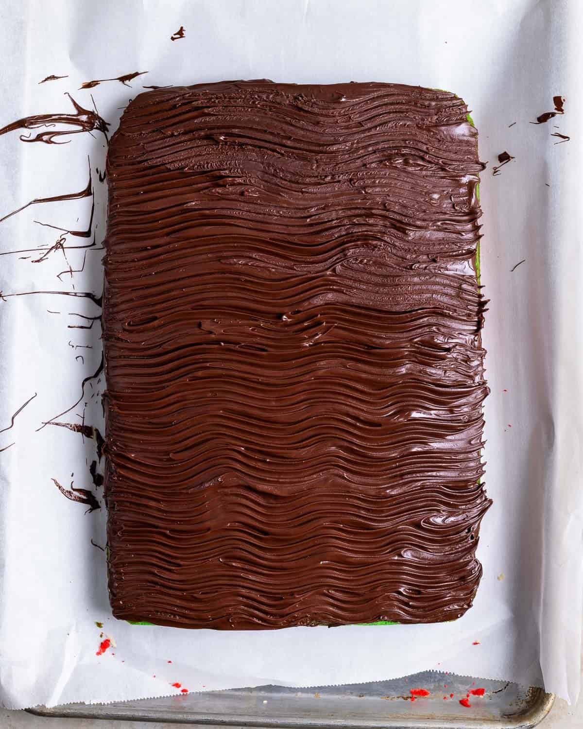 Chocolate spread onto the slab of cookies with a wavy pattern formed by fork tines.