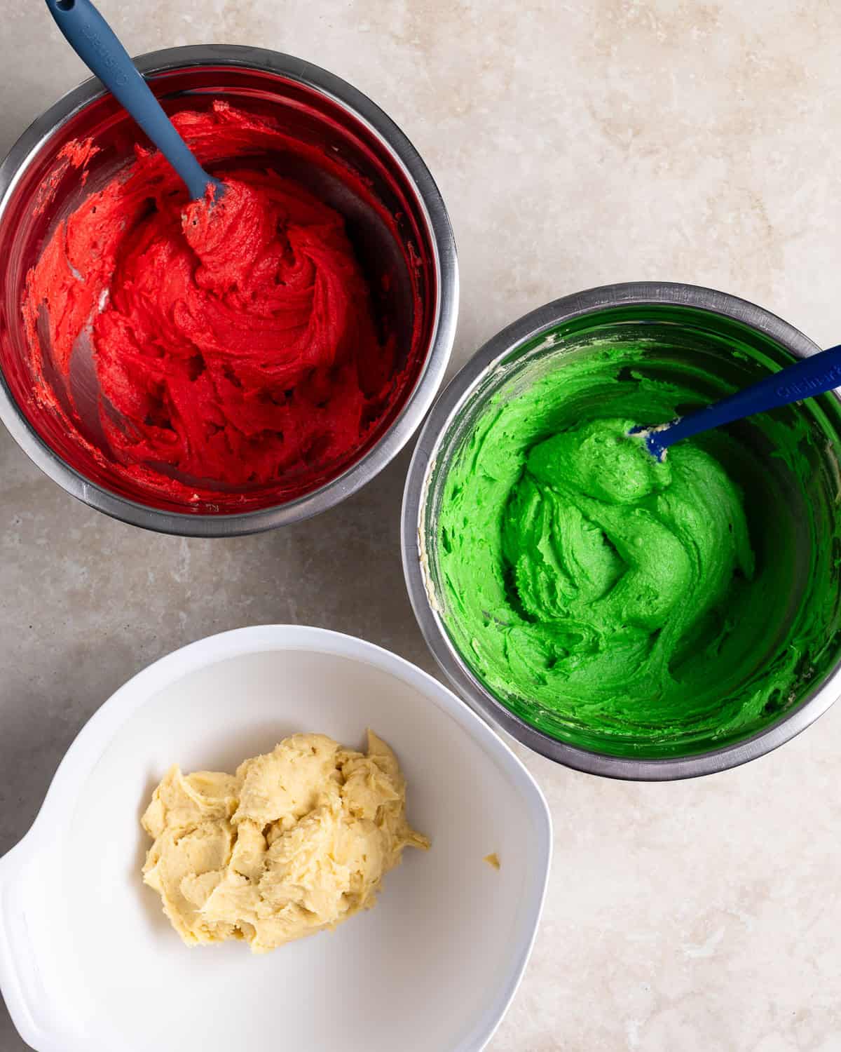 Red, green, and white rainbow cookie batters in separate bowls.